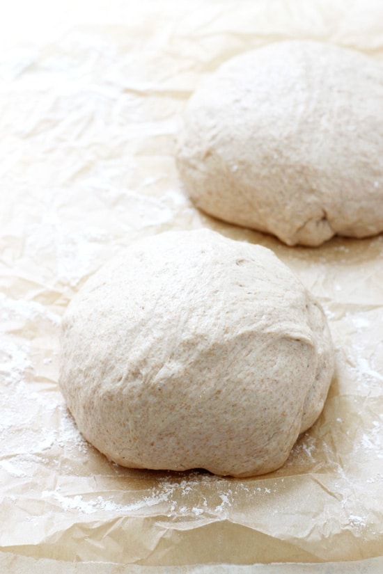 Two balls of Wheat Pizza Dough on parchment paper.