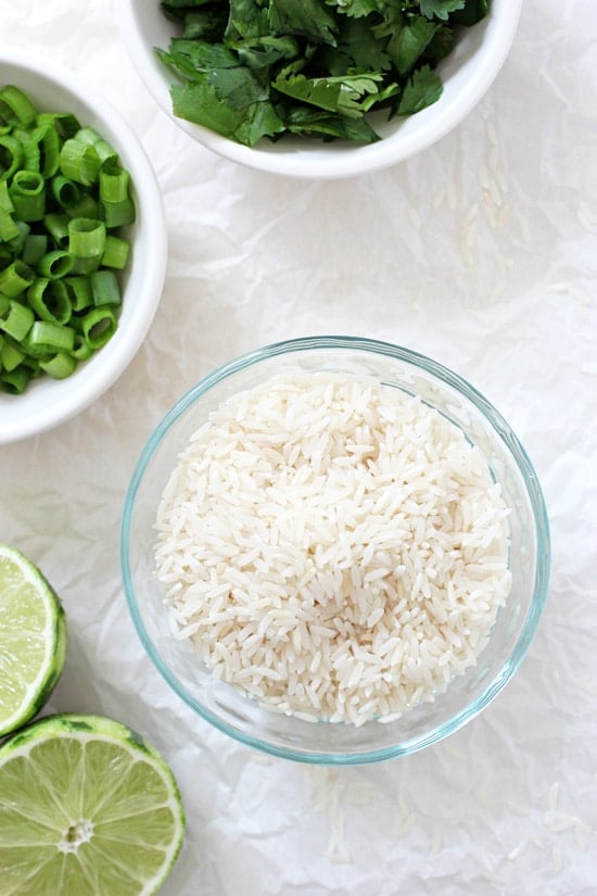 Small bowls filled with dry rice, green onions and cilantro.