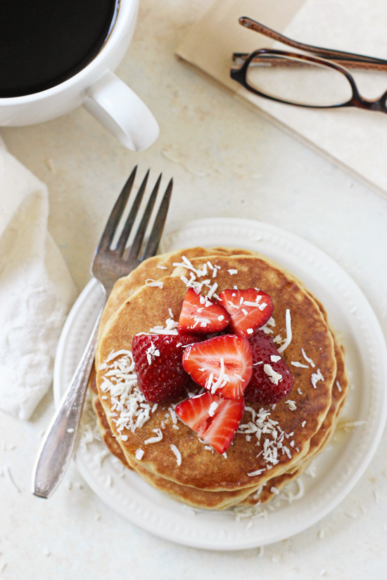 Several Macadamia Pancakes on a plate topped with strawberries.