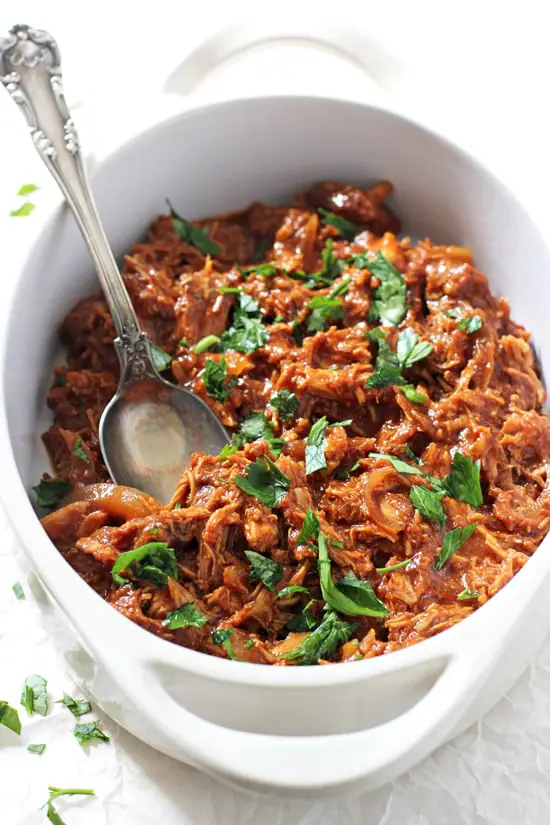 A white baking dish filled with Crockpot Pulled BBQ Chicken.