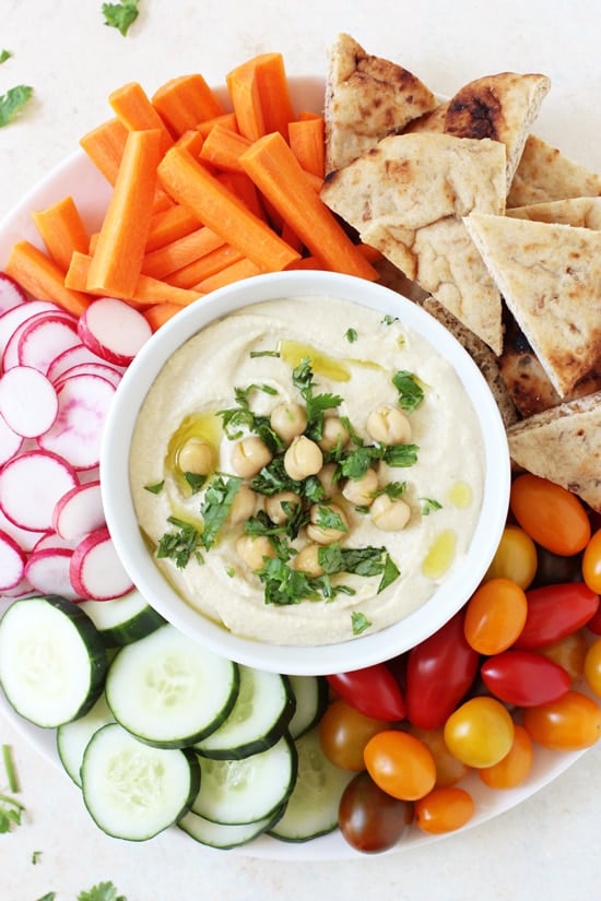 A serving platter filled with Restaurant-Style Hummus, veggies and pita bread.