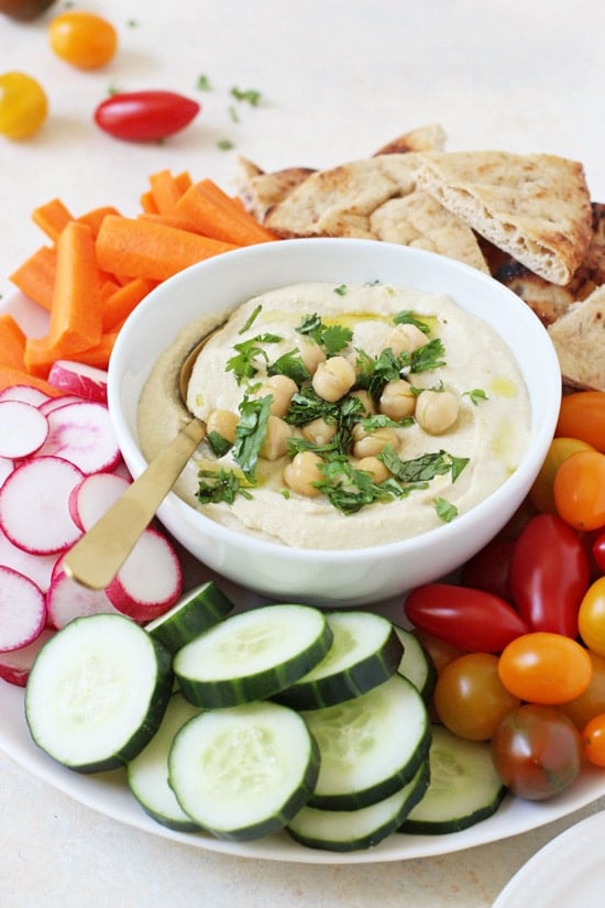 A serving platter with Restaurant Hummus and sliced veggies.