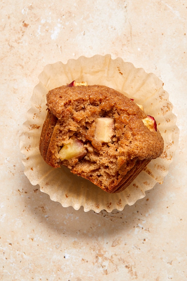 A Dairy Free Applesauce Muffin in the wrapper with a bite taken out.