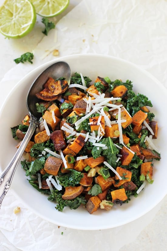 A white bowl filled with Warm Sweet Potato Salad and a serving spoon.