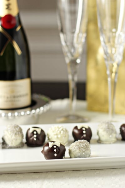 Bride and Groom Truffles on a white platter with champagne in the background.