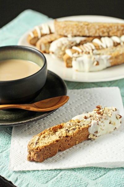 Pecan Biscotti on a plate and napkin with a cup of coffee.