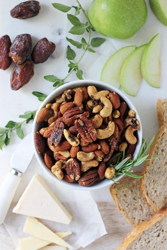 Spiced Rosemary Nuts on a marble platter with bread, fruit and dates.