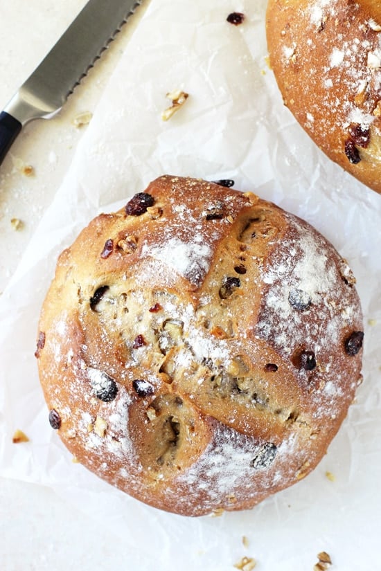 Two loaves of Cranberry Walnut Bread on parchment paper with a knife.