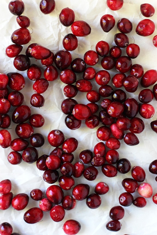 Fresh cranberries scattered on crinkled parchment paper.