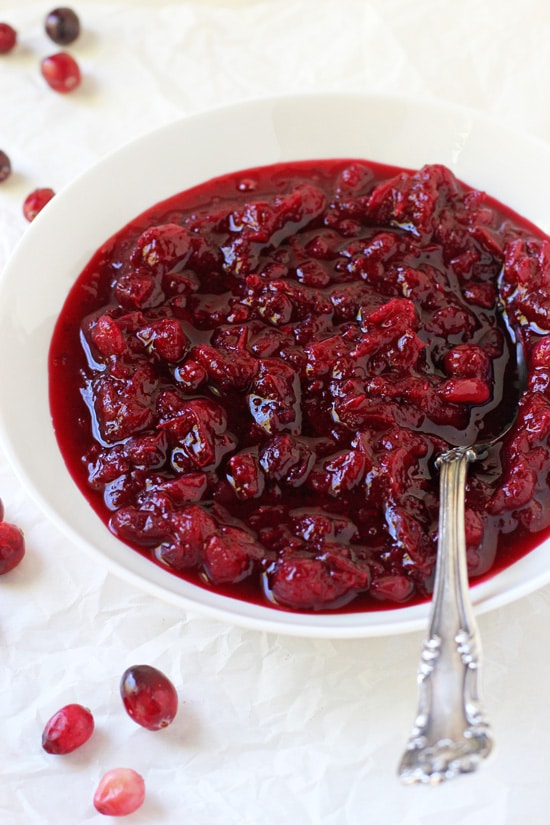 A white bowl filled with Cranberry Orange Sauce with a spoon in the dish.