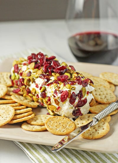 Baked Goat Cheese on a platter with crackers and a cheese knife.