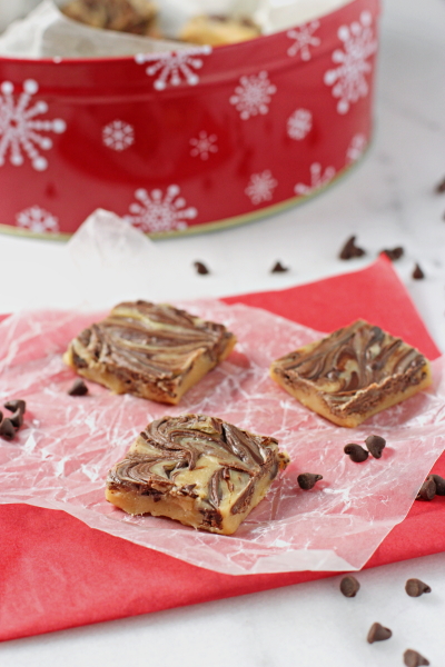 Three pieces of Chocolate Peanut Butter Swirl Fudge on parchment paper.