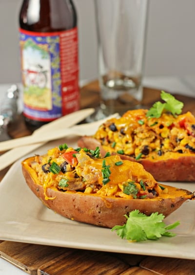 Two Loaded Sweet Potato Skins on a plate with a can of beer in the background.