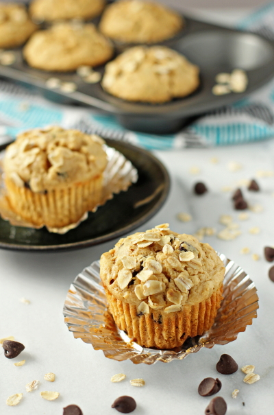 Two Peanut Butter Oatmeal Chocolate Chip Muffins on a marble surface.
