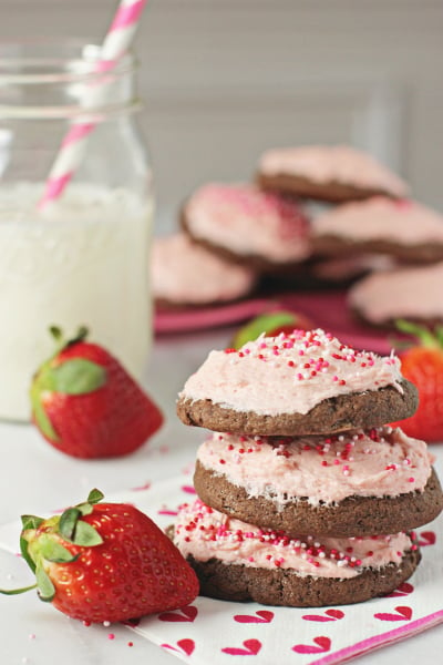 Several Strawberry Frosted Cookies stacked on a napkin.