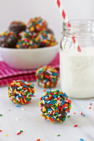 Several Baked Donut Holes with a glass of milk.