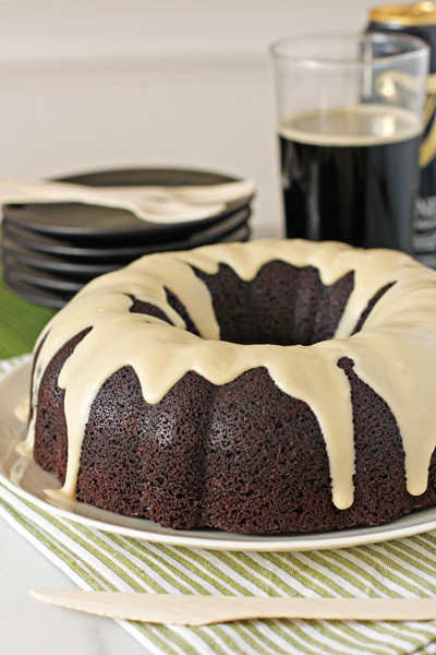 A Chocolate Stout Cake on a white plate with beer in the background.