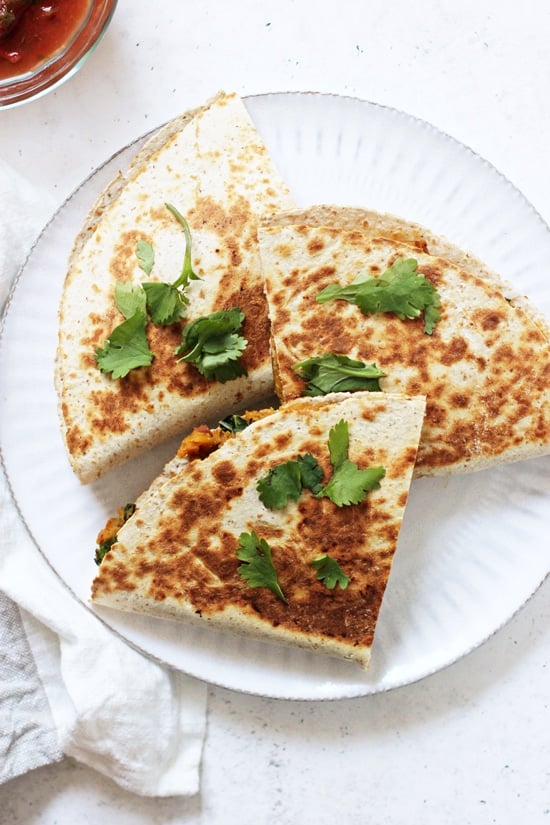 A white plate with three triangles of Sweet Potato Black Bean Quesadillas.