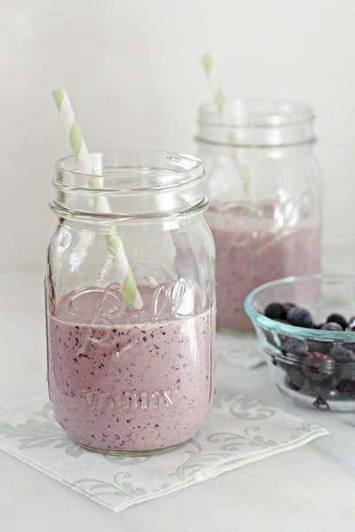 Two glasses of Blueberry Peanut Butter Smoothie with blueberries to the side.