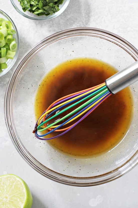 A glass bowl filled with honey lime chipotle dressing with a whisk in the bowl.