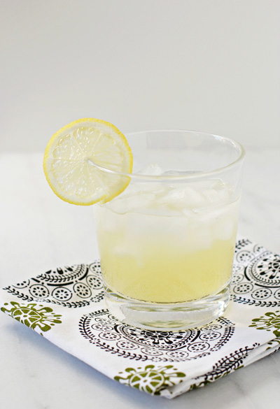 A Honey Margarita in a glass with a slice of lemon.