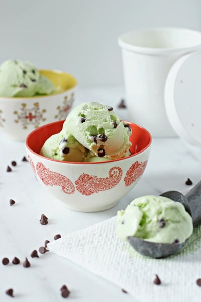 Two colorful bowls filled with Fresh Mint Ice Cream and a scooper to the side.