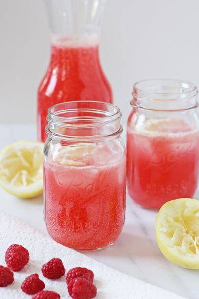 Two glasses and a carafe of Sparkling Raspberry Lemonade.