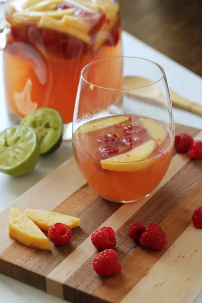 A glass of Raspberry Peach Sangria set on a cutting board.
