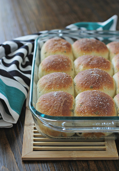 A glass baking dish filled with Fresh Herb Dinner Rolls.