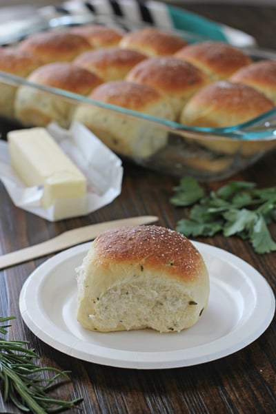 A Herb Dinner Roll on a white plate with more in the background.