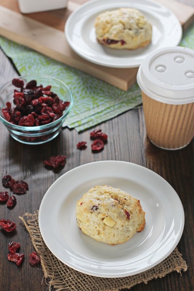 Two Cranberry White Chocolate Scones on white plates.