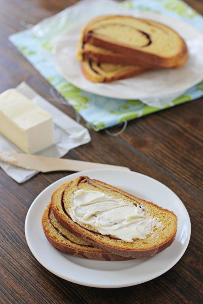 Slices of Pumpkin Yeast Bread on plates with one buttered.
