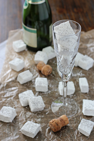 Homemade Champagne Marshmallows in a champagne glass and on parchment paper.