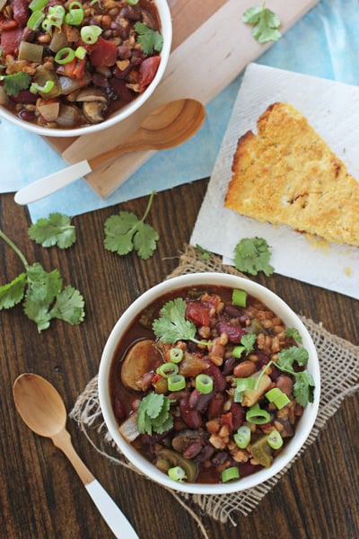 Two white bowls filled with Chili with Farro with cornbread to the side.