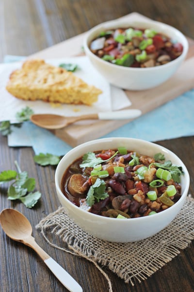 Two bowls filled with Crockpot Vegetarian Chili with cornbread to the side.