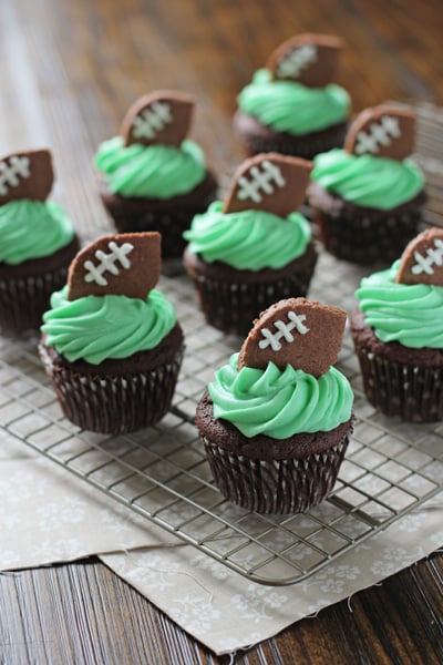 Several Football Cupcakes on a wire cooling rack.
