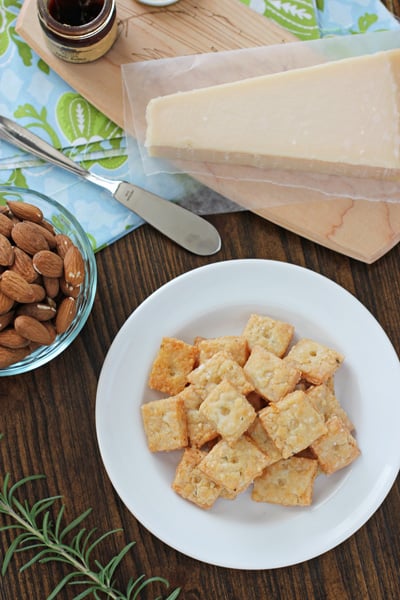 Rosemary Crisps on a white plate with almonds and cheese to the side.