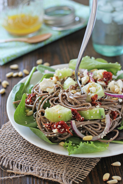 A Soba Noodle Salad on a plate with a fork twirling some noodles.