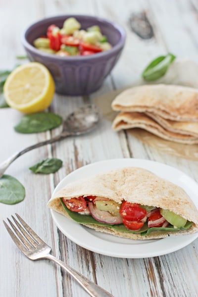 A Mediterranean Pita Pocket on a plate with veggies and pita bread to the side.