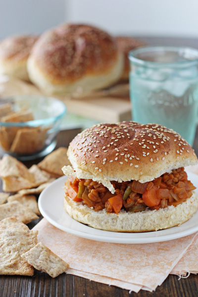 A Vegan Sloppy Joe on a white plate with water and chips.