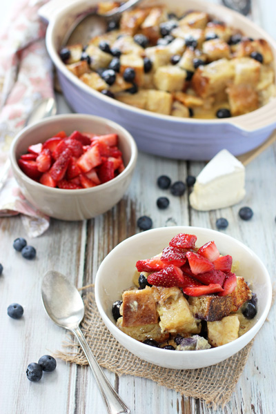 A white bowl with a serving of Berry Breakfast Bake with more in the background.