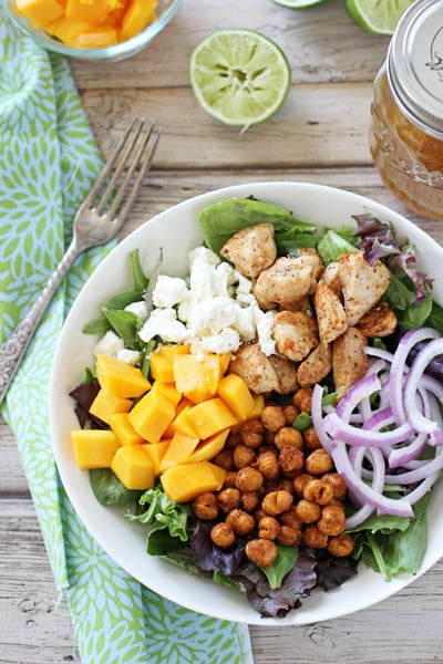 A white bowl filled with Chicken and Mango Salad with a fork to the side.