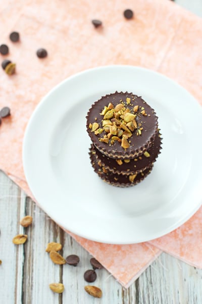 Several Dark Chocolate Almond Butter Cups stacked on a white plate.