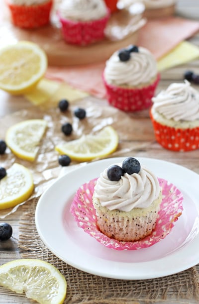 A Lemon Poppy Seed Cupcake on a plate with more in the background.