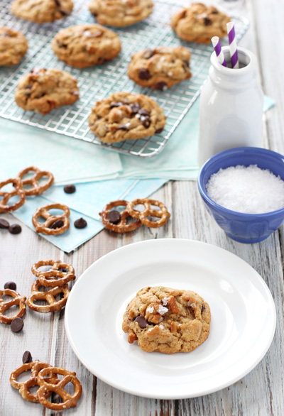 A Peanut Butter Chocolate Chip Pretzel Cookie on a plate with more in the background.