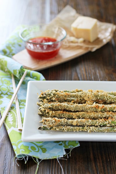 Parmesan Crusted Asparagus on a white serving platter with sauce to the side.