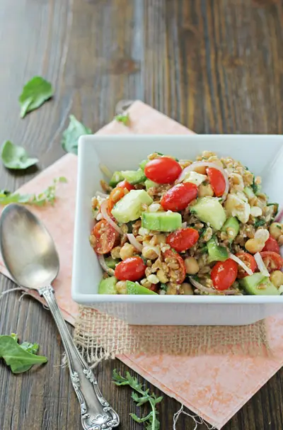 A white serving dish filled with Mediterranean Farro Salad.