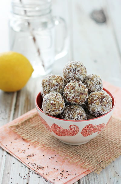 A colorful dish filled with Lemon Energy Balls with water in the background.