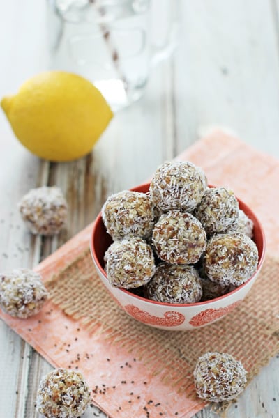 A bowl filled with Lemon Coconut Energy Balls with some spilling out the sides.