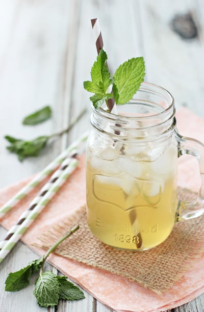 A glass filled with Vanilla Honey Iced Tea Lemonade with fresh mint.